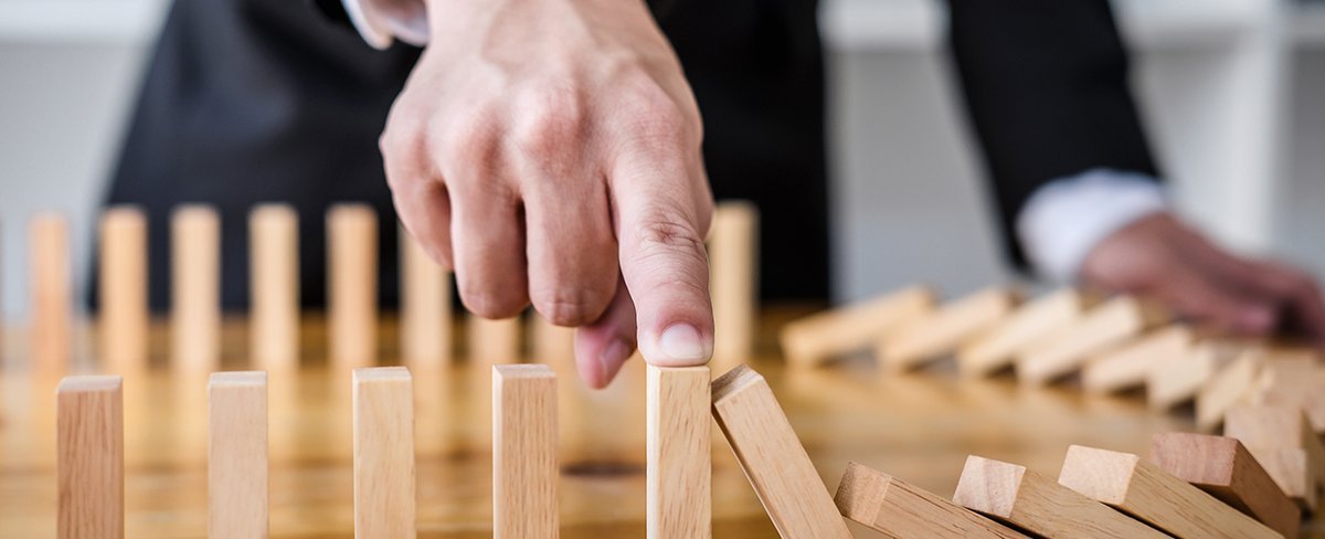 Holzspielstrategie. Ein Mann im Anzug hält einen Bauklotz mit dem Finger fest Holzspielstrategie. Ein Mann im Anzug hält einen Bauklotz mit dem Finger fest